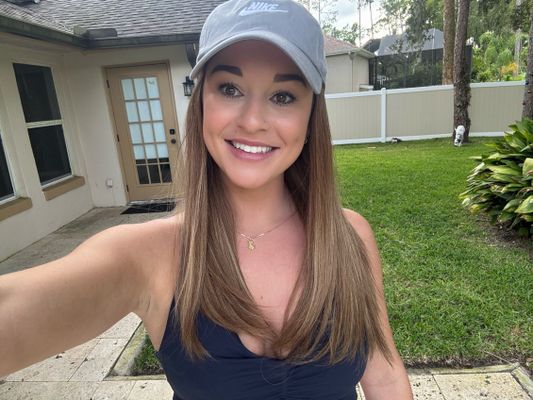 A_woman_wearing_a_gray_Nike_baseball_cap_and_navy_tank_top_taking_a_se.jpg
